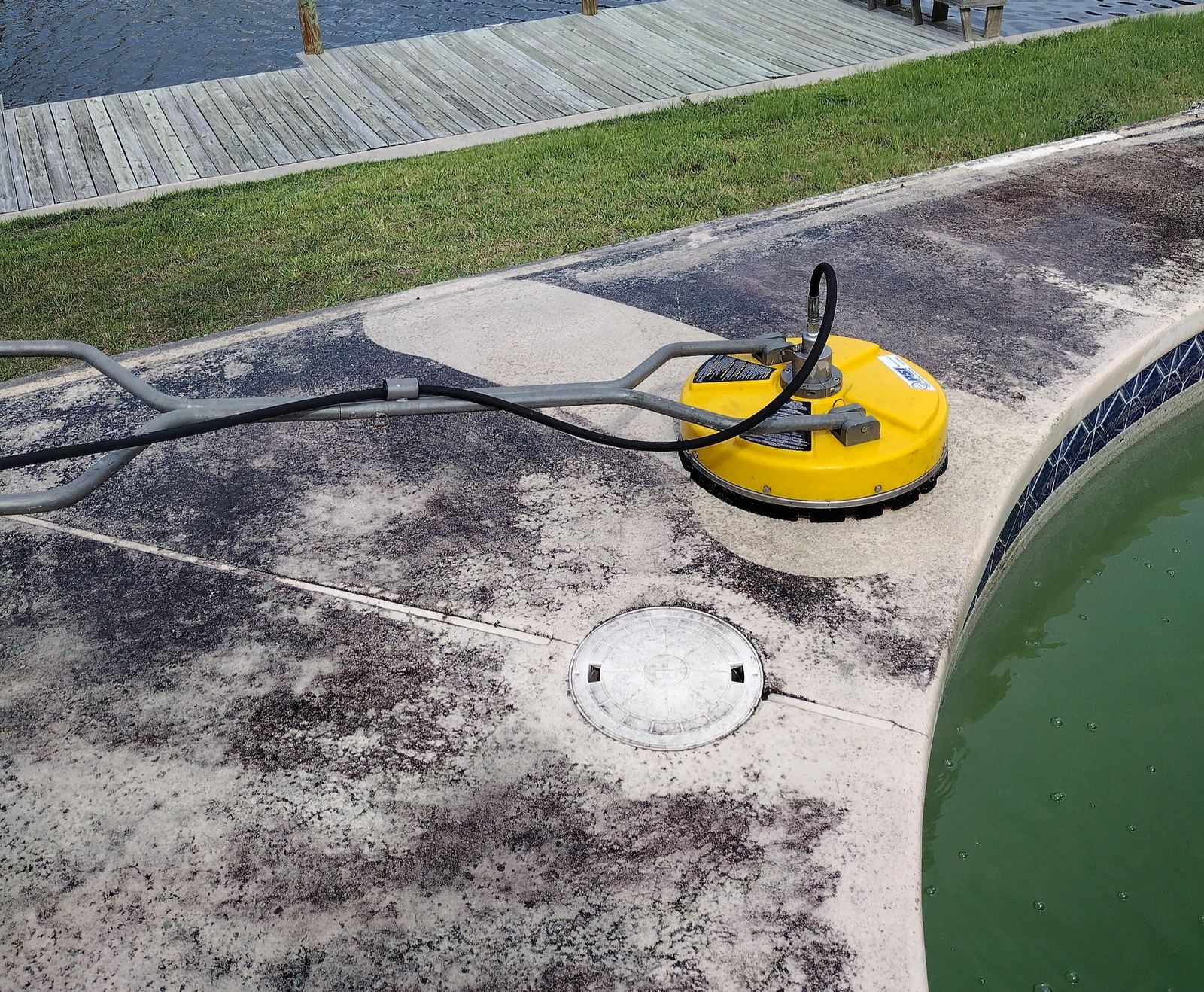 Pool deck mid-cleaning, showing the sharp contrast between the cleaned and still-grimy concrete